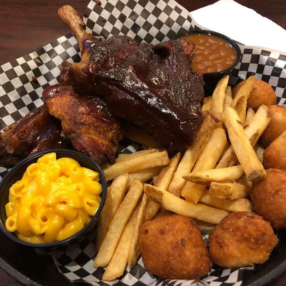 Ribs with barbecue sauce, french fries, hush puppies, mac and cheese, and baked beans.
